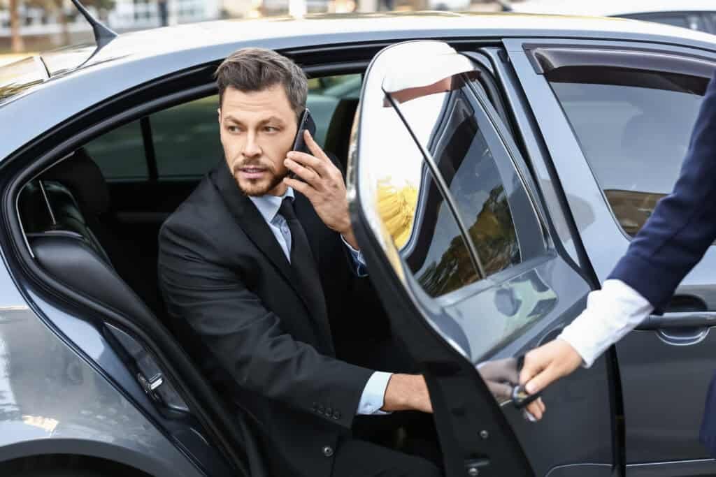 Businessman exiting a luxury car assisted by chauffeur – Arman Cabs corporate travel service