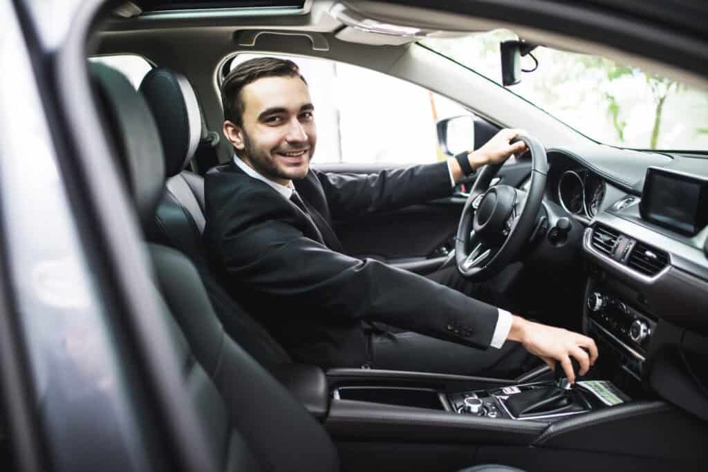Private hire driver in a smart suit seated in a modern vehicle, looking confident and ready for work